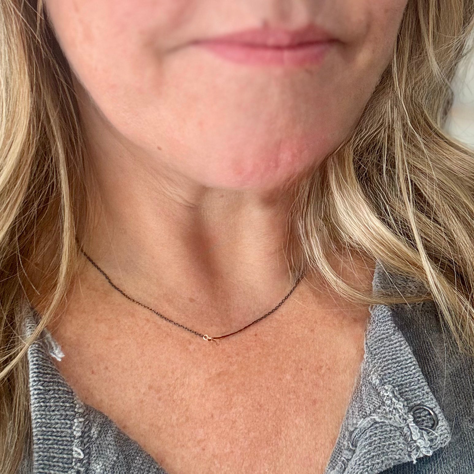 close-up image of female model wearing handmade necklace with 3 tiny 14K yellow gold wire hearts on oxidized sterling silver chain